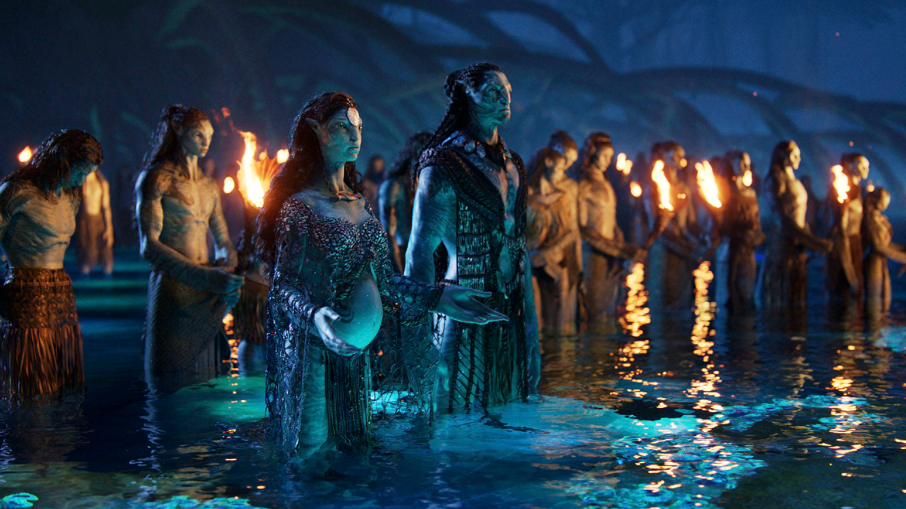Джейк и Нейтири стоят в воде вместе с другими На’ви в «Аватар: Путь Воды».