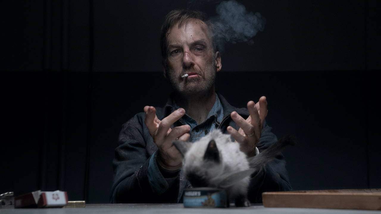 Боб Оденкирк курит сигарету с котом перед ним в Никто