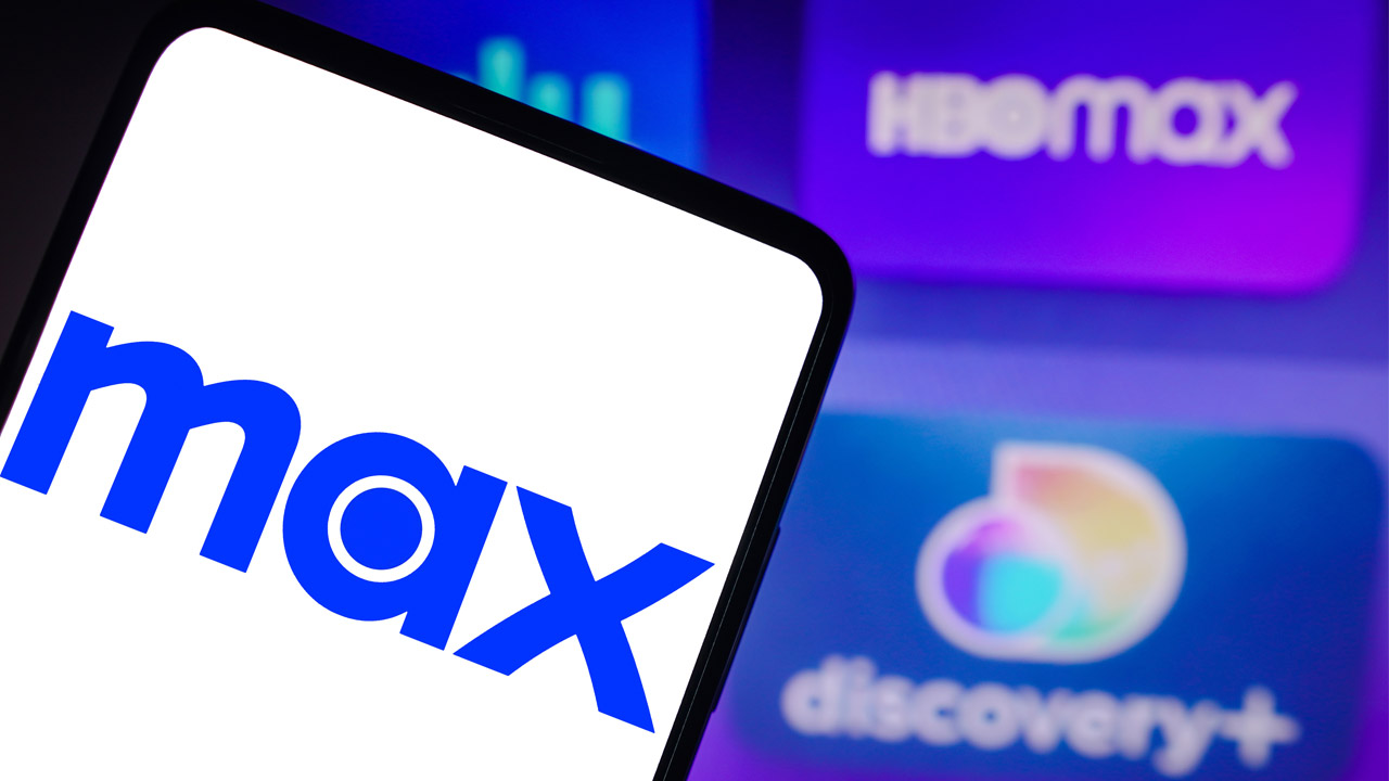 На этой фотоиллюстрации логотип Max отображается на смартфоне, а на заднем плане — логотип HBO Max и Discovery+.
