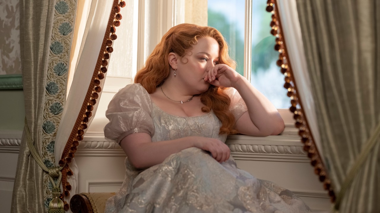 Penelope assise près d'une fenêtre appuyée contre son bras dans la saison 3 de Bridgerton.