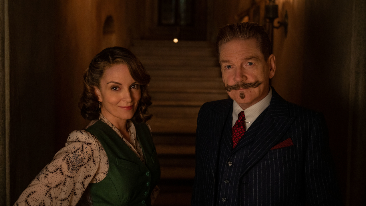 Tina Fey und Kenneth Branagh posieren für ein Foto in einem von Fackeln beleuchteten Korridor in A Haunting in Venice.
