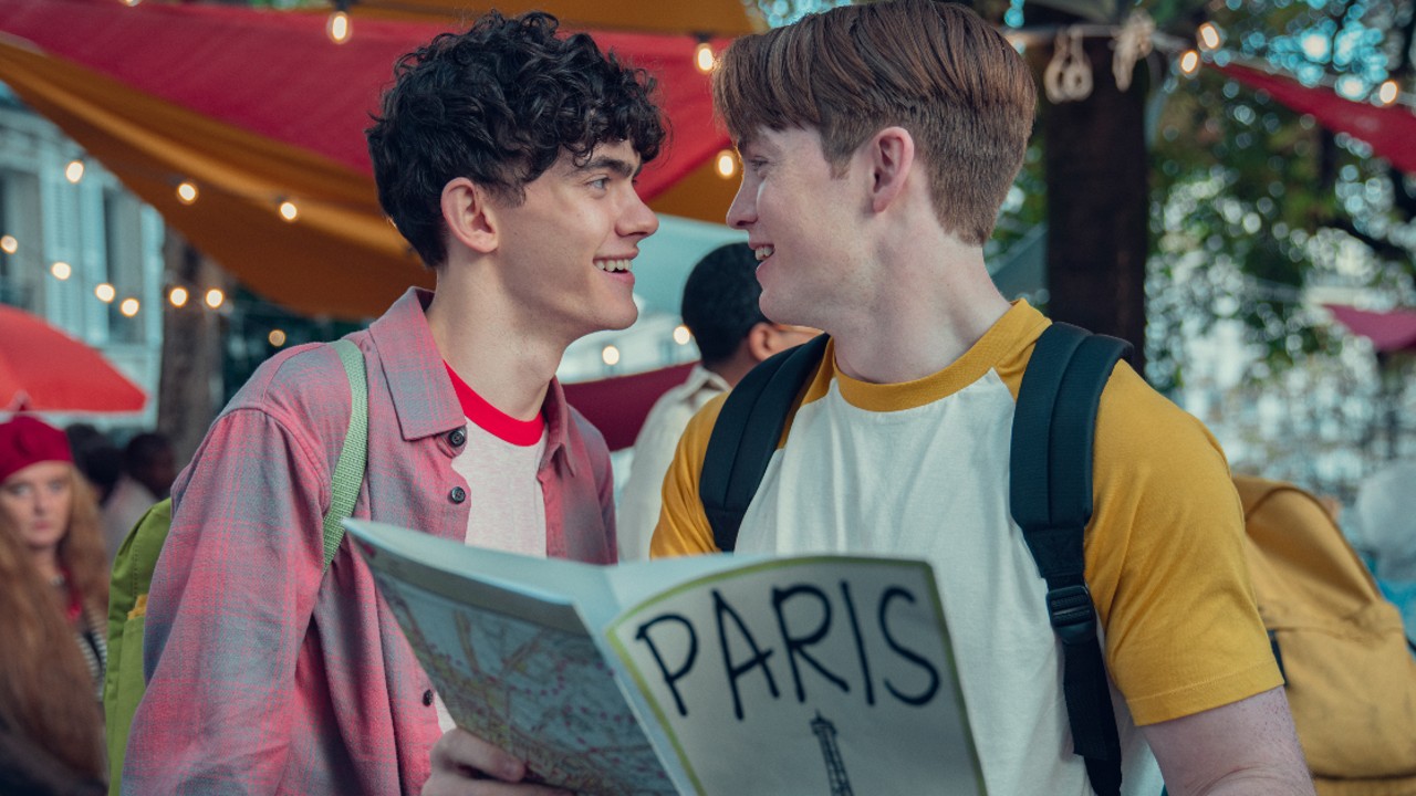 Nick und Charlie halten eine Paris-Karte in der Hand und lächeln einander an.