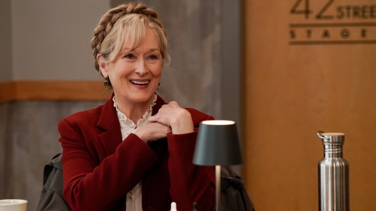 Meryl Streep lächelt an einem Tisch und liest in Staffel 3 von Only Murders in the Building.