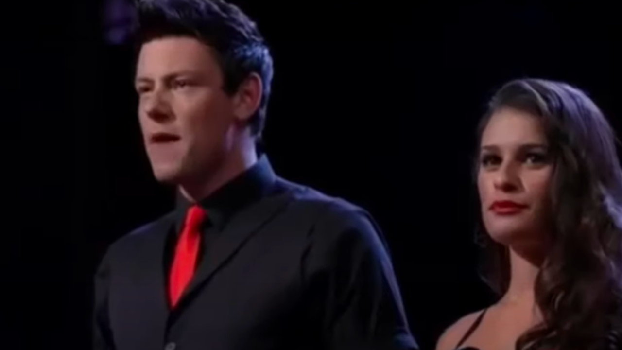 Кори Монтейт поет на сцене в костюме в Glee.