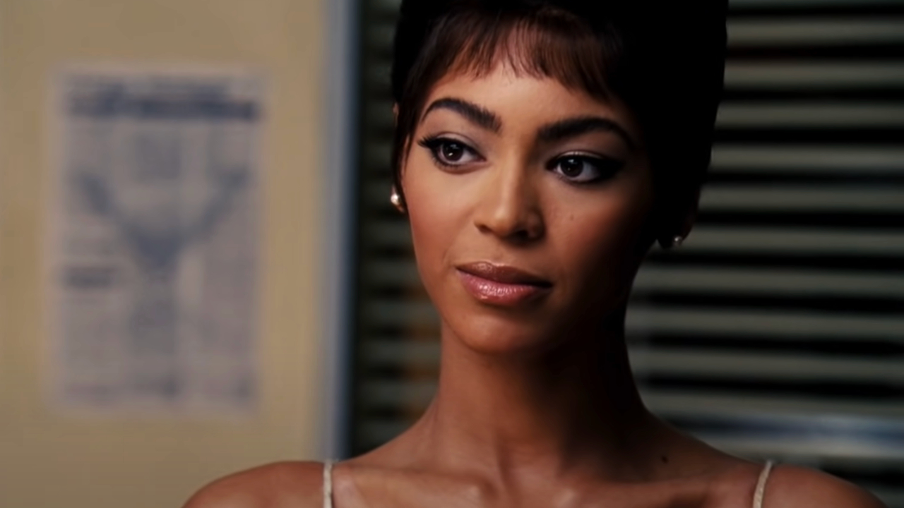 Beyoncé à moitié souriante dans une coiffure et un costume rétro dans Dreamgirls.