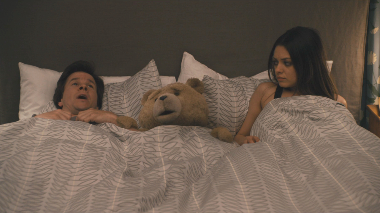 Mark Wahlberg und Ted lagen verängstigt im Bett, während Mila Kunis Ted ungläubig beobachtete.