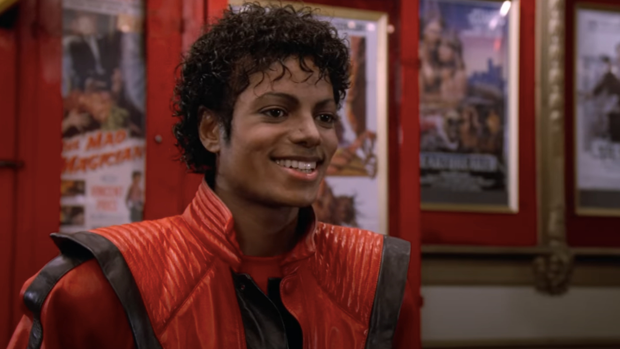Michael Jackson lächelt in einer Kinolobby in Thriller.