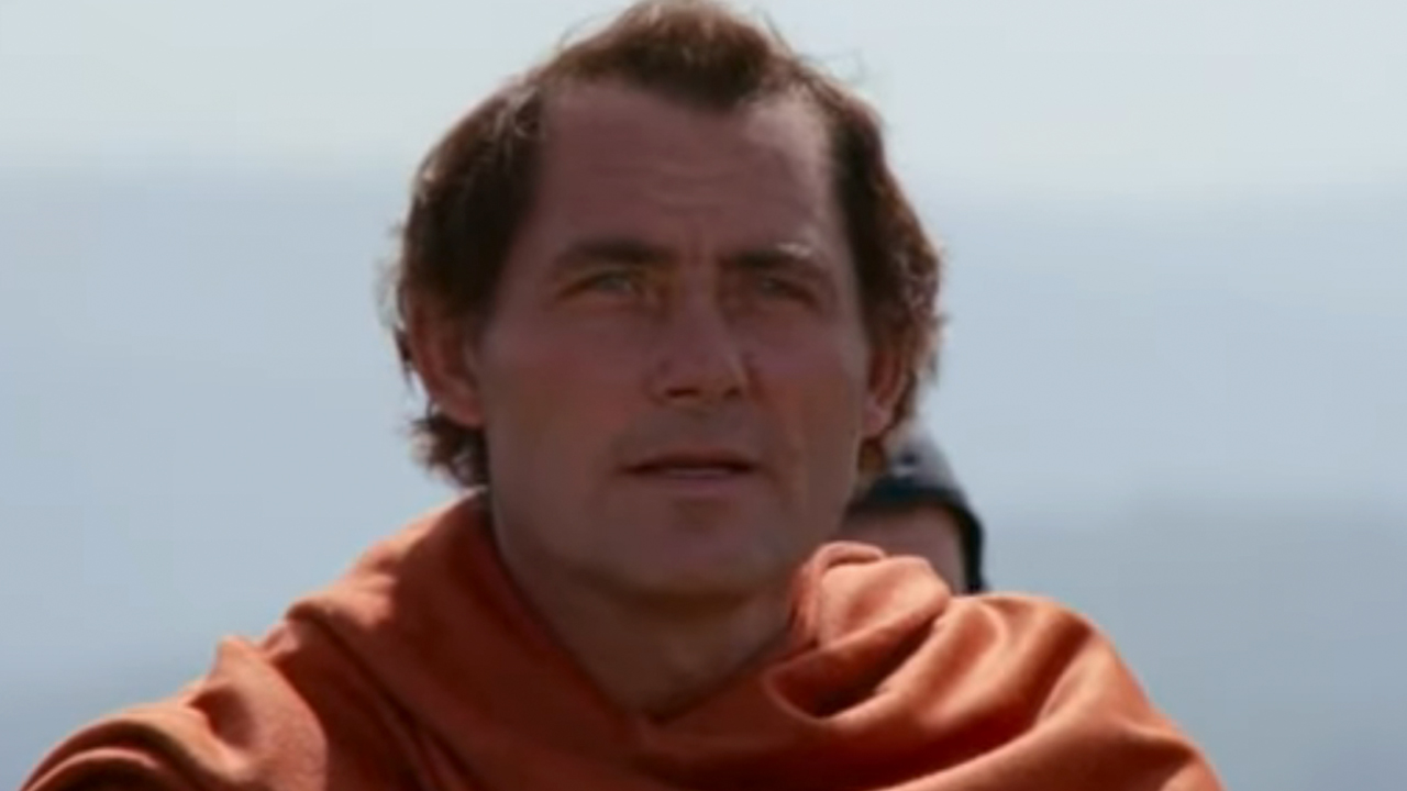 Un gros plan de Robert Shaw portant une cape orange dans Robin et Marian