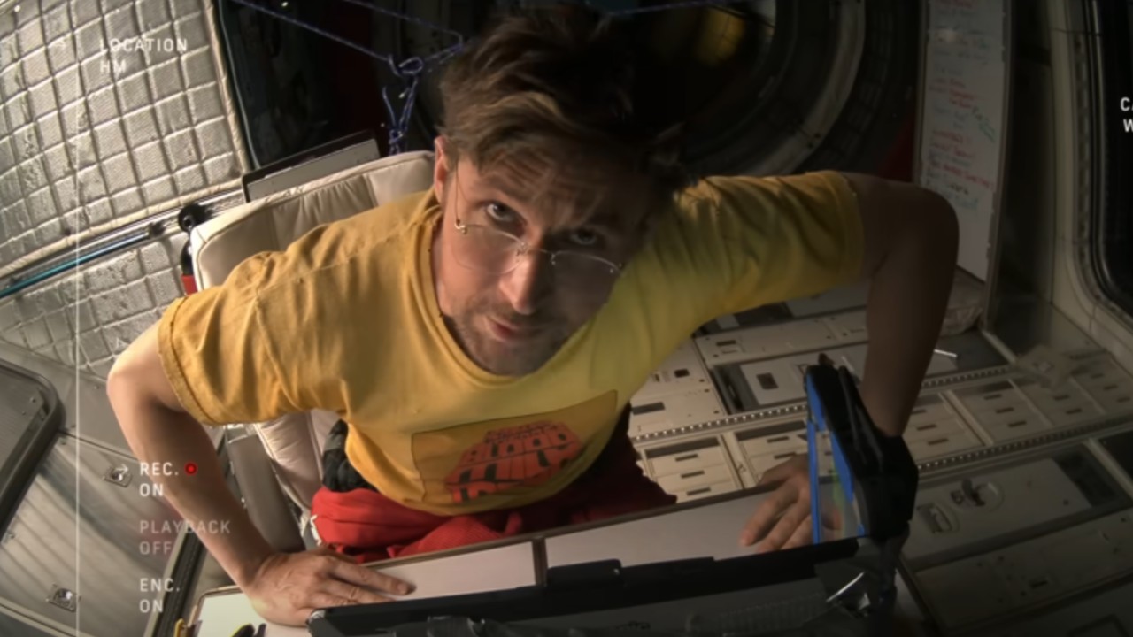 Ryland parle devant une caméra vidéo et lève les yeux.