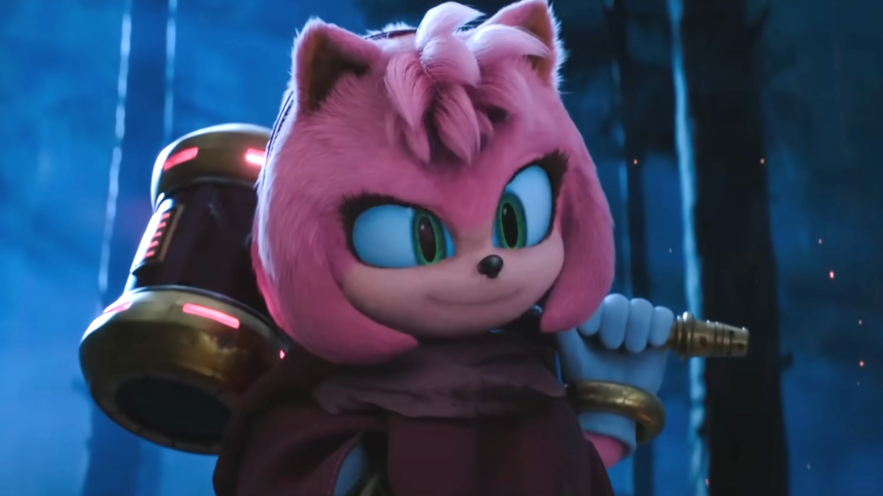 Amy Rose sourit en tenant son marteau dans les bois sombres de Sonic the Hedgehog 3.