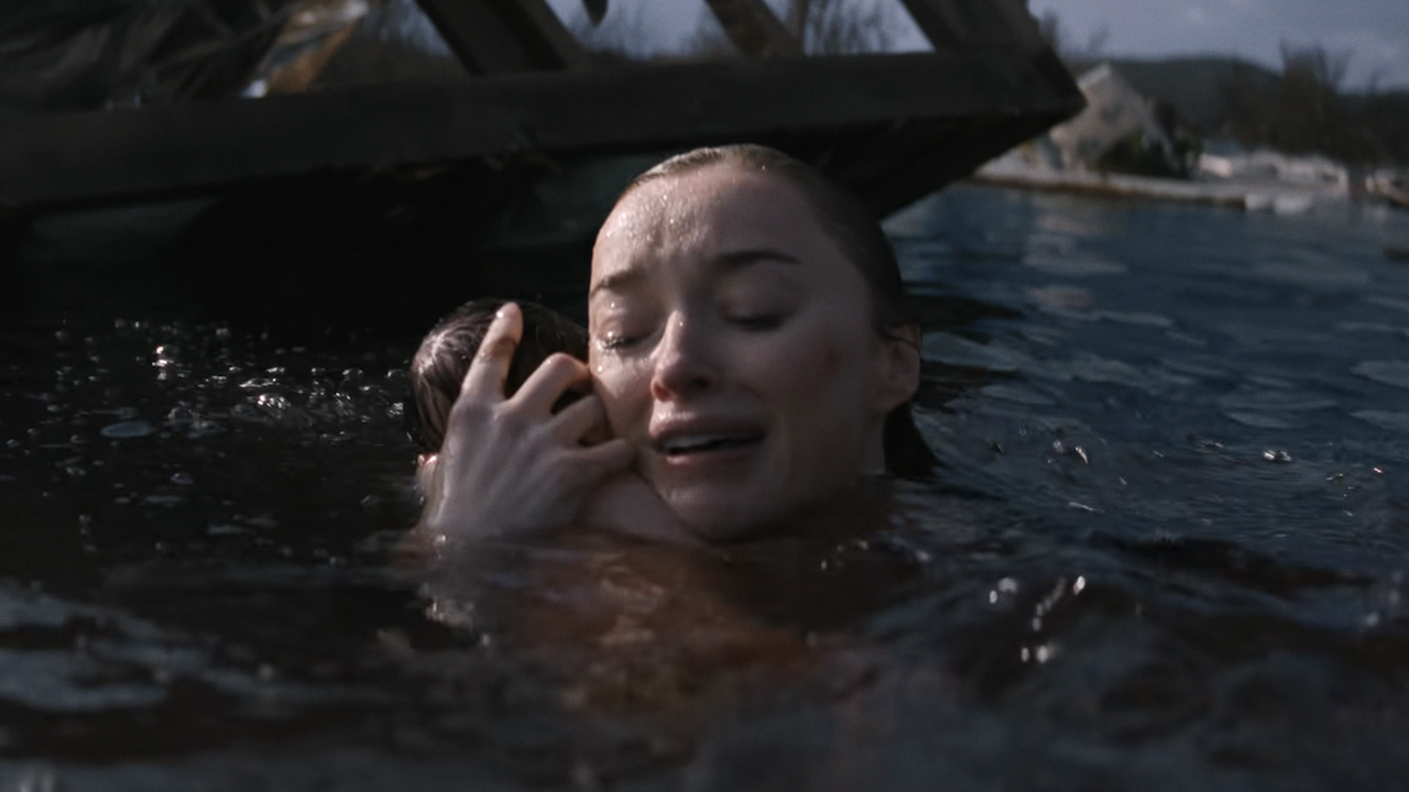 Лиза держит новорожденного ребенка на плече, находясь в паводке в фильме Netflix «Трэш»