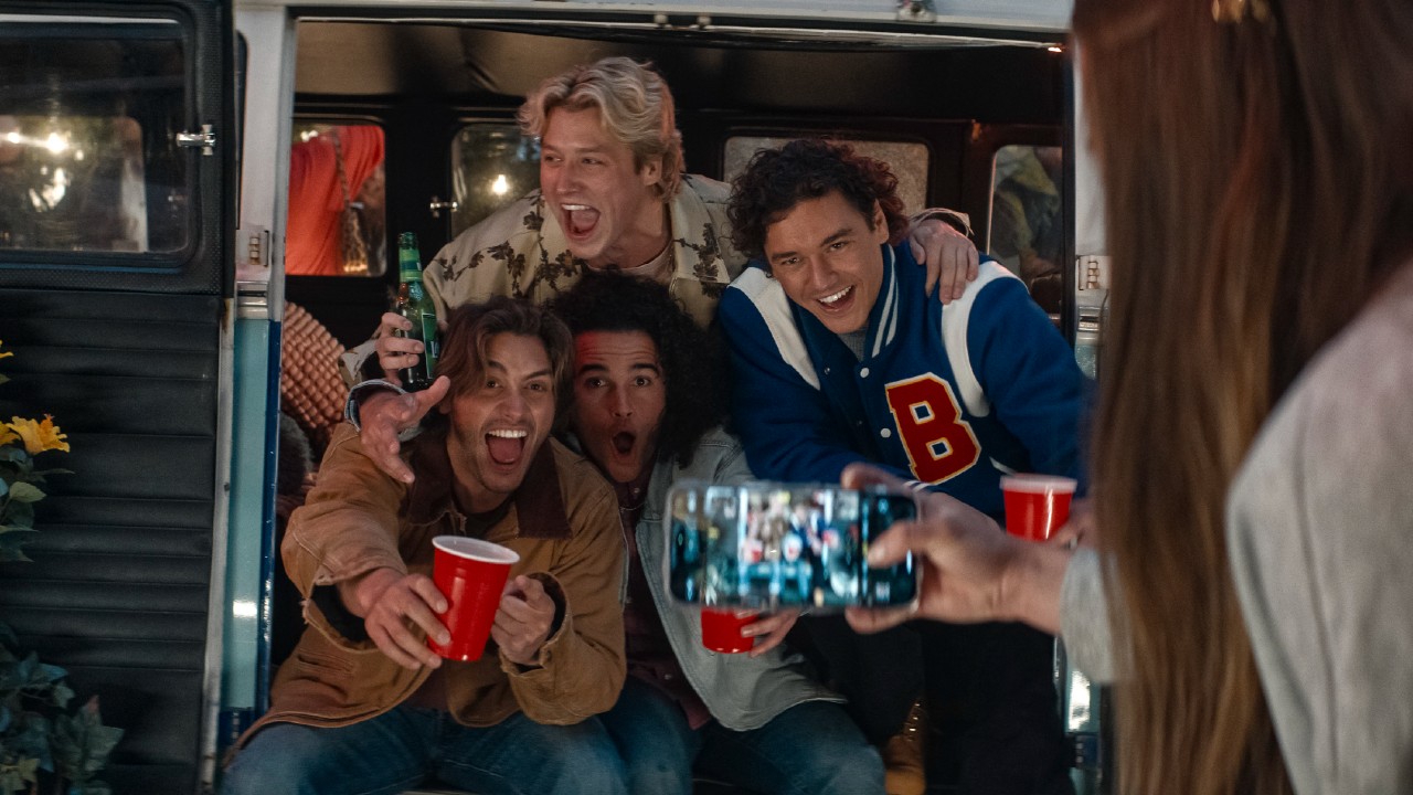 De gauche à droite : John Logan, John Tucker et Garrett Graham souriants et assis ensemble et Dean DiLaurentes debout au-dessus d'eux, les bras autour de leurs épaules.