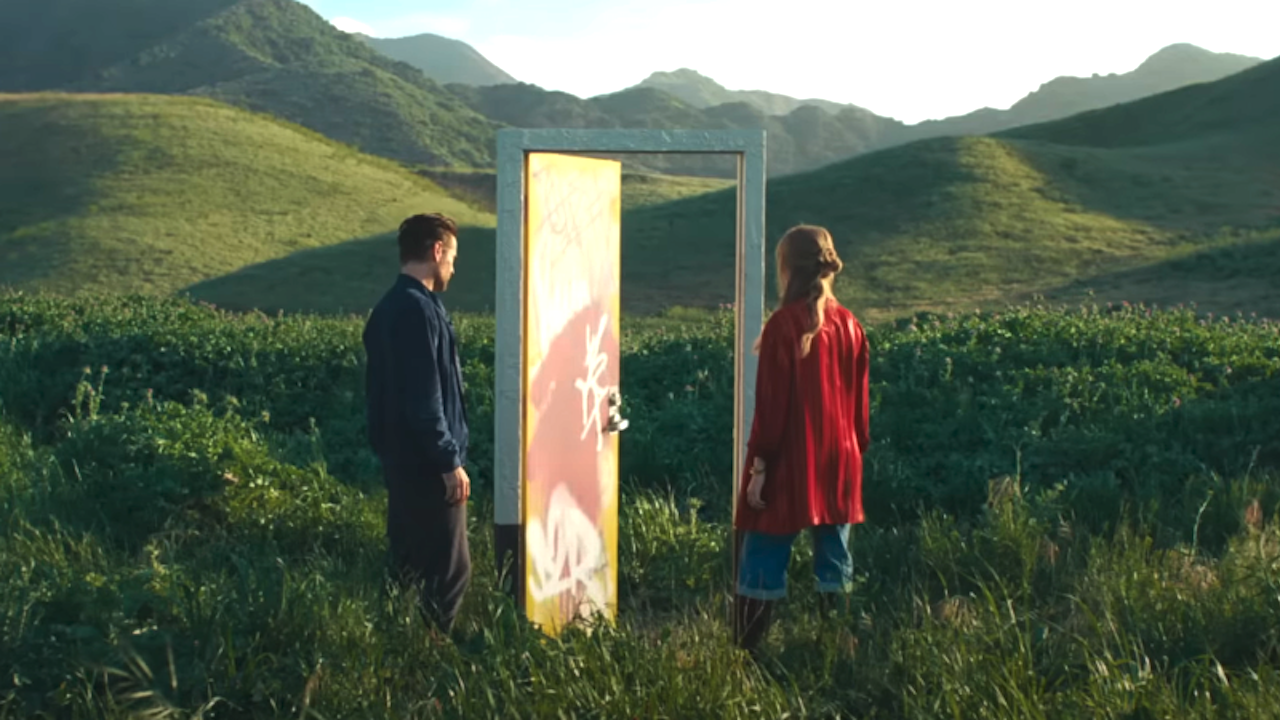 Colin Farrell et Margot Robbie debout près d'une porte au milieu d'une campagne vallonnée dans A Big Bold Beautiful Journey still